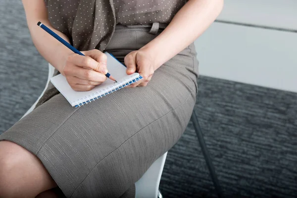 woman writing on notepad