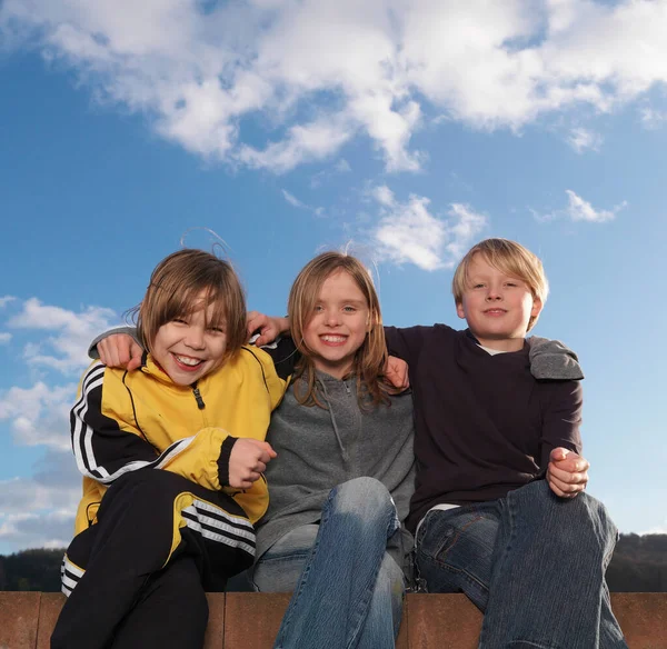 Retrato Grupo Niños Sentados Pared Baja Sonriendo —  Fotos de Stock
