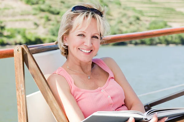 Mature reading book woman on a boat holiday