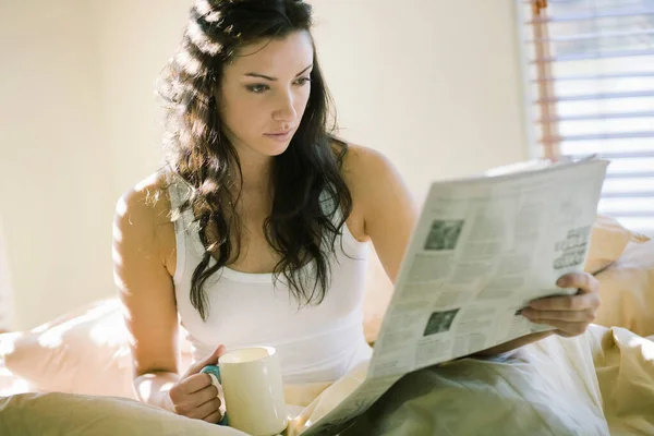 Kobieta Czytająca Gazetę Łóżku Filiżanką — Zdjęcie stockowe