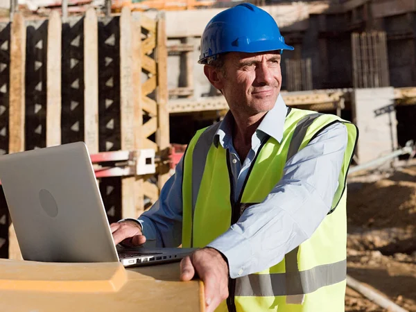 Mature man uusing laptop on construction site