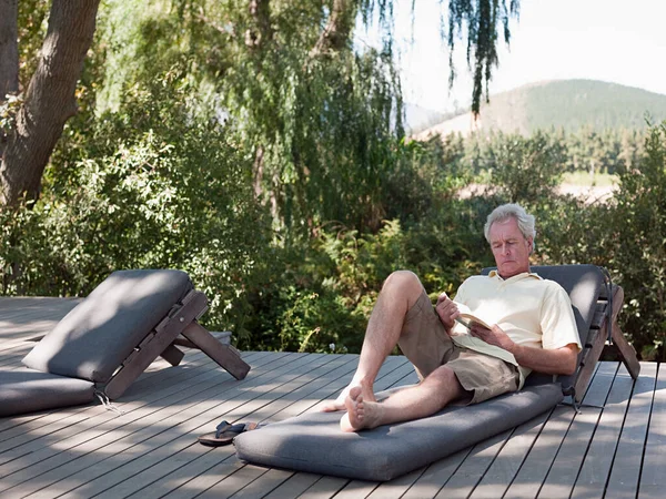 Senior man reading on sun lounger
