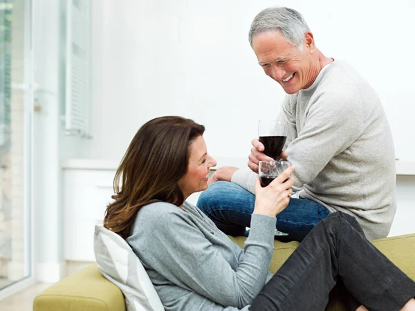 ワインが付いているソファーに座っている熟女のカップル — ストック写真