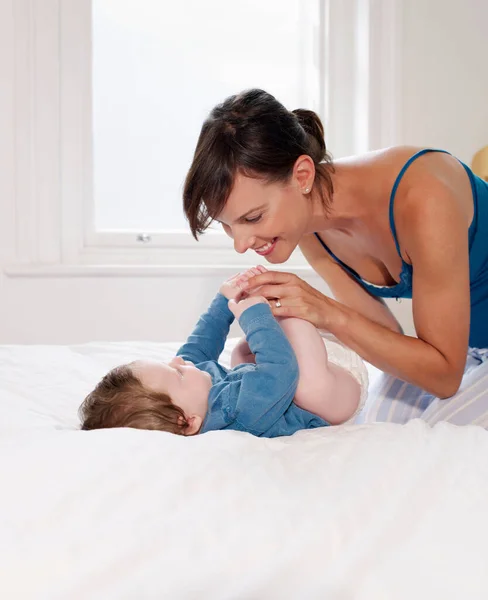 赤ちゃんのベッドの上に横になっている笑顔の母 — ストック写真