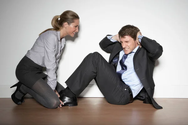 Woman helping business man exercise