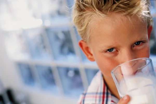 Chlapec Pije Mléko Při Pohledu Kamery — Stock fotografie