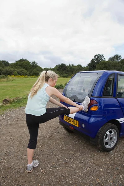 Young woman exercising by electric car — Stock Photo, Image