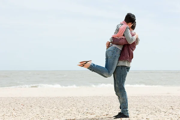 Homem junto ao mar levantando namorada — Fotografia de Stock