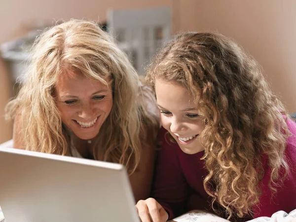 若いです女性とお母さん見ますノートパソコンでベッド — ストック写真
