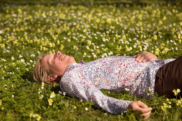 Человек Лежащий Траве Весенними Цветами — стоковое фото