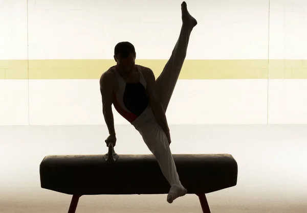 Male gymnast performing on pommel horse