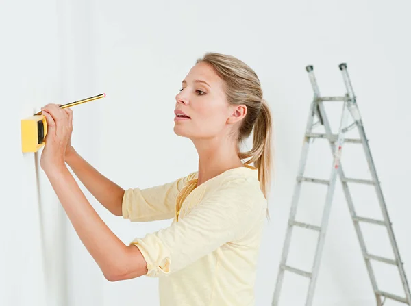 Young woman using spirit level on wall