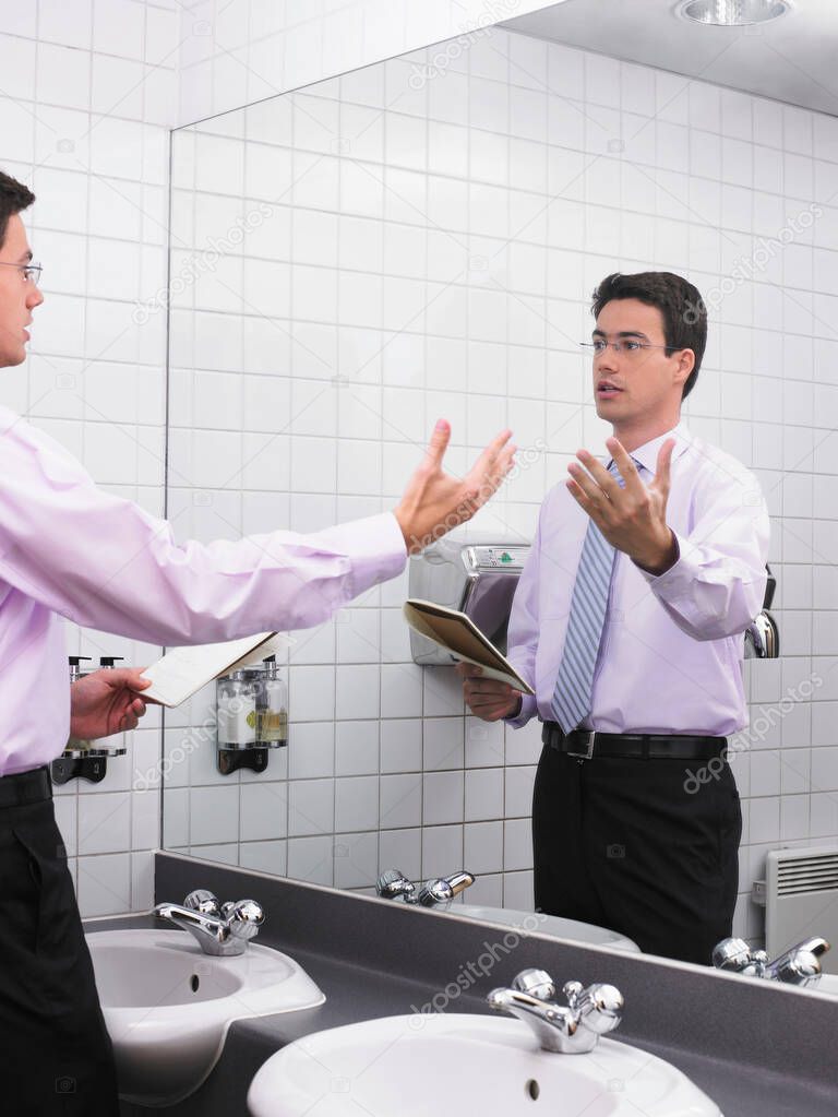 Man practicing speech in office washroom mirror