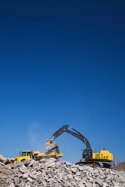 Excavator on piles of rubble — Stok fotoğraf