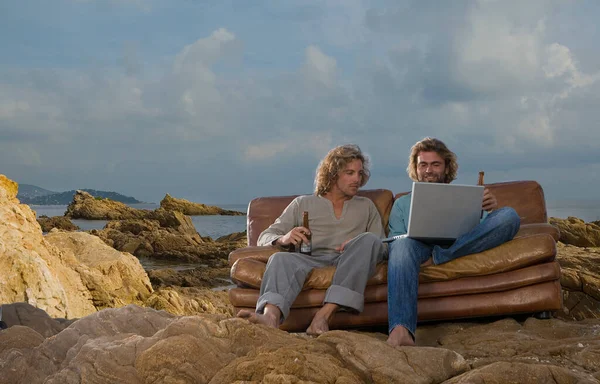 Men with laptop and beer on couch, beach — Stock Photo, Image