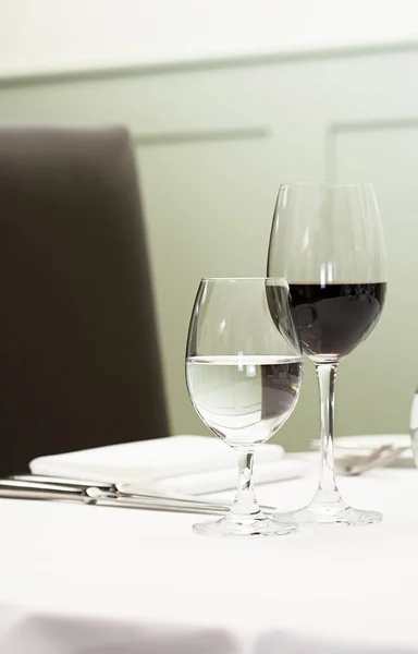 A glass of water and red wine on a table — 图库照片