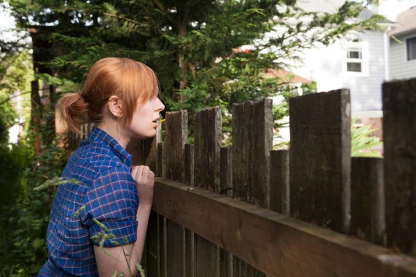 隣の庭に柵を見下ろす若い女性 — ストック写真