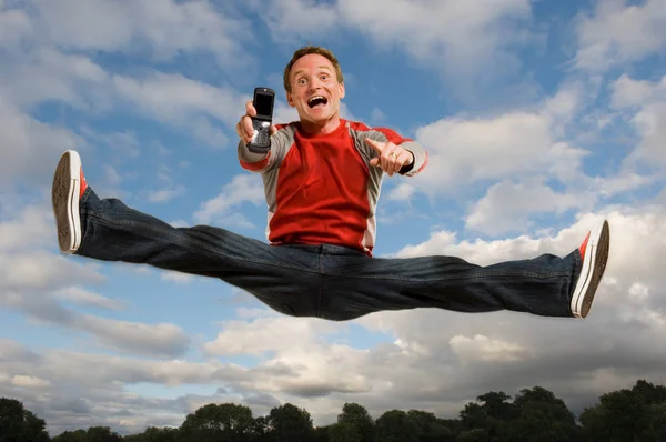 Mann springt mit Handy in die Luft — Stockfoto