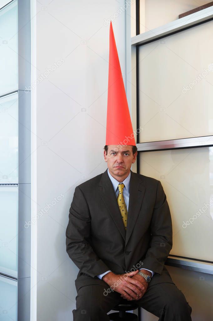 lonely adult businessman wearing dunce cap