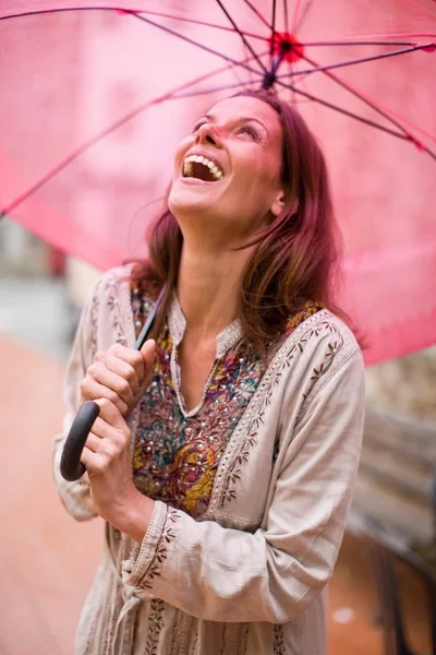 ピンクの傘が笑いながら下に女性 — ストック写真