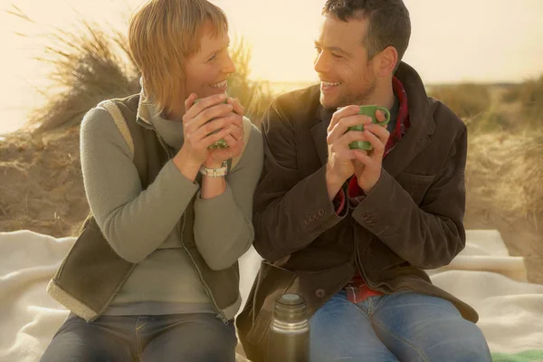在海滩上喝酒瓶咖啡的夫妇 — 图库照片