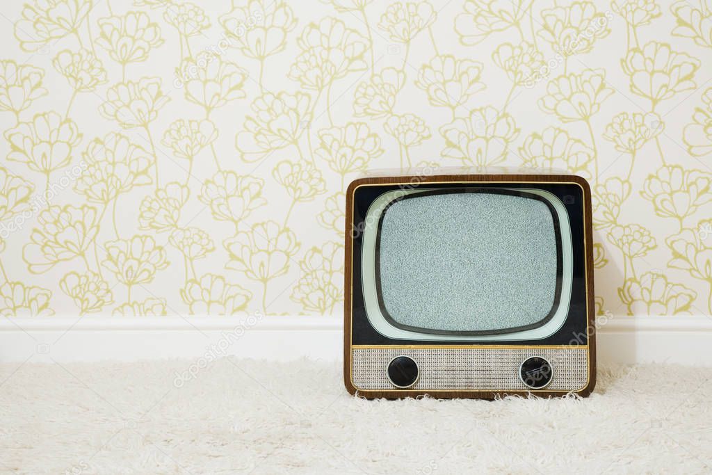 Retro television in room with patterned wallpaper