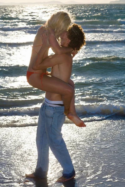 Joven cple beso en la puesta del sol playa — Foto de Stock