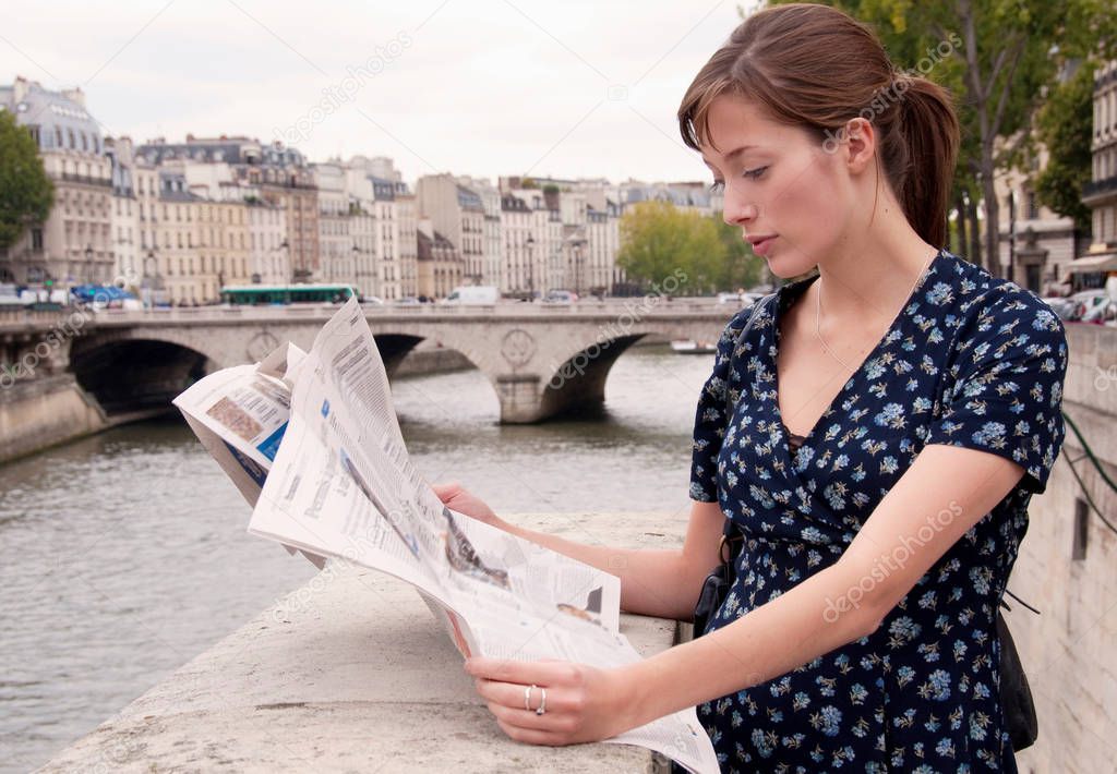 Woman reads newspaper in Paris