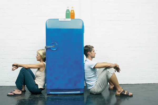 Couple seated against a fridge — kuvapankkivalokuva