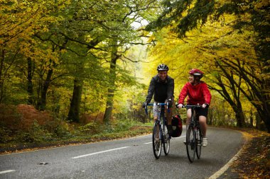 Çiftler köy yolunda bisiklet sürüyor.