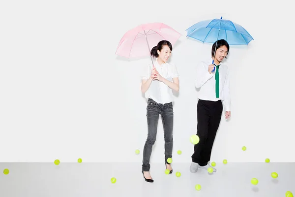 Para Parasolkami Spadającymi Piłkami Tenisowymi — Zdjęcie stockowe