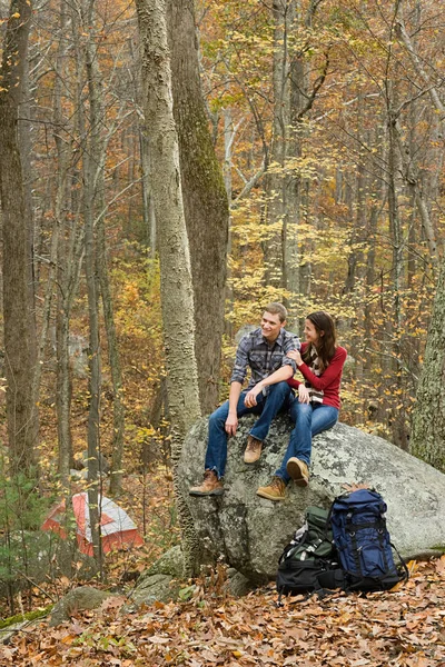 森の中の岩の上に座っている若いカップル — ストック写真