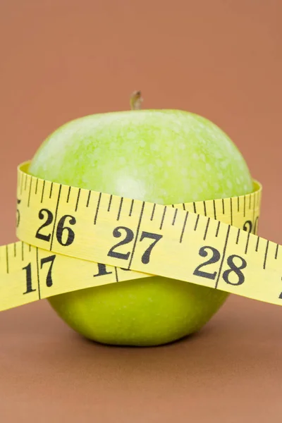 A tape measure wrapped around an apple — 스톡 사진