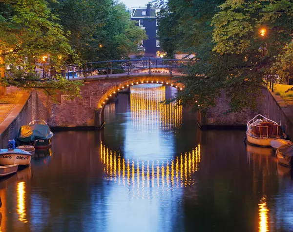 Kanalbrücke in der Abenddämmerung beleuchtet, Amsterdam, Niederlande — Stockfoto