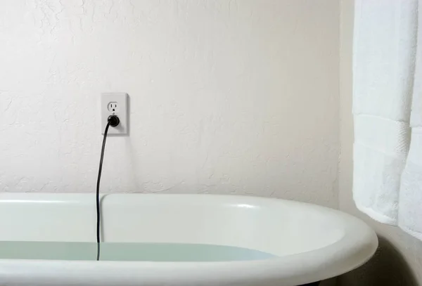 Prise et câble en direct dans l'eau du bain — Photo