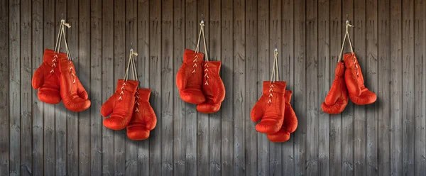 Riga di guanti da boxe rossi appesi alla parete rivestita in legno — Foto Stock