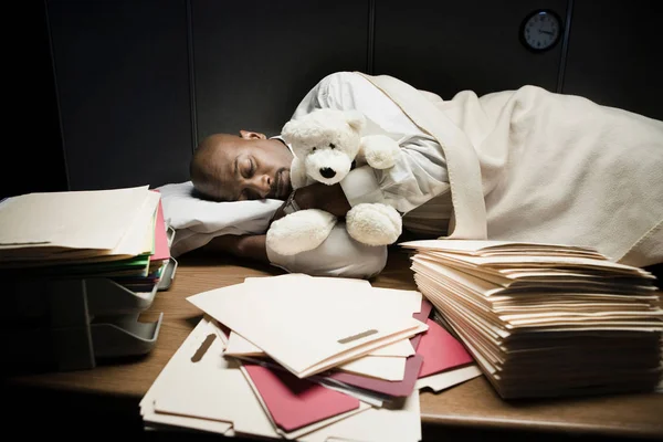 Man with stuffed animal sleeping at desk
