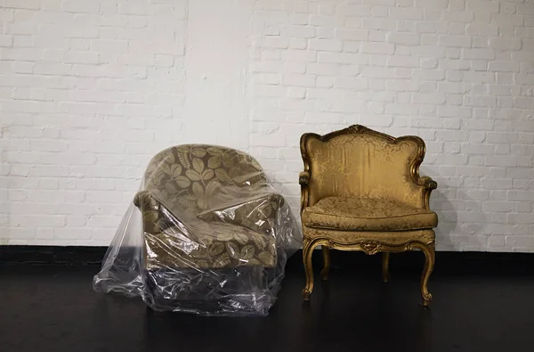 두 개의 안락의자, 하나는 폴리 텐 으로 덮혀 있고, 하나는 상점 방에 있다 — 스톡 사진