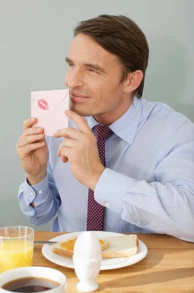 Man taking a smell at a love letter — Stock Photo, Image