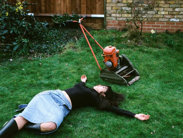 女人躺在割草机旁 — 图库照片