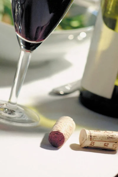 Γυαλί και μπουκάλι κόκκινο κρασί στο τραπέζι — Φωτογραφία Αρχείου