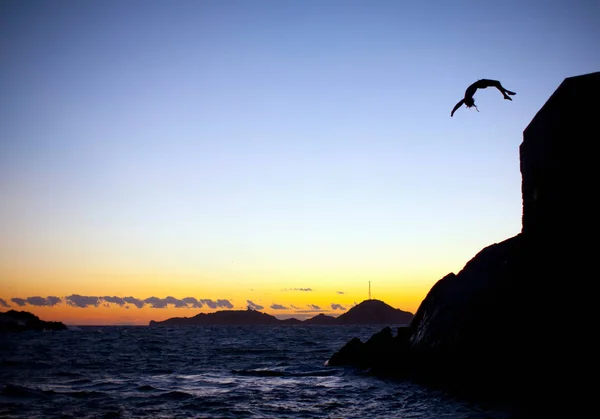 青い空を飛び越える男の崖 — ストック写真