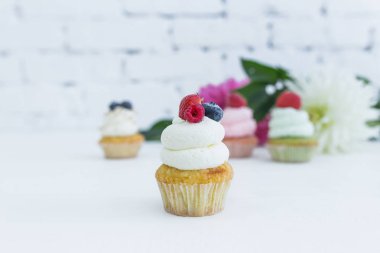 Taze çilek çiçekleri ve yaprakları ile çeşitli cupcakes.