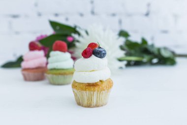 Taze çilek çiçekleri ve yaprakları ile çeşitli cupcakes.