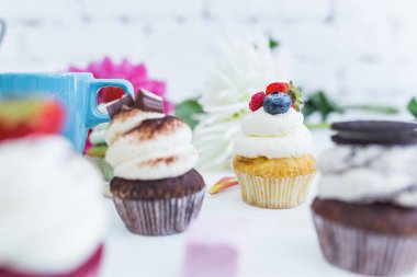 Taze çilek çiçekler ve yapraklar, bir fincan çay ya da kahve ile cupcakes.