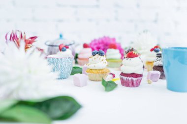 Taze çilek çiçekler ve yapraklar, bir fincan çay ya da kahve ile cupcakes.