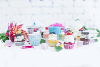 Taze çilek çiçekler ve yapraklar, bir fincan çay ya da kahve ve bir su ısıtıcısı ile cupcakes.