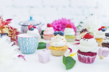 Taze çilek çiçekler ve yapraklar, bir fincan çay ya da kahve ile cupcakes.