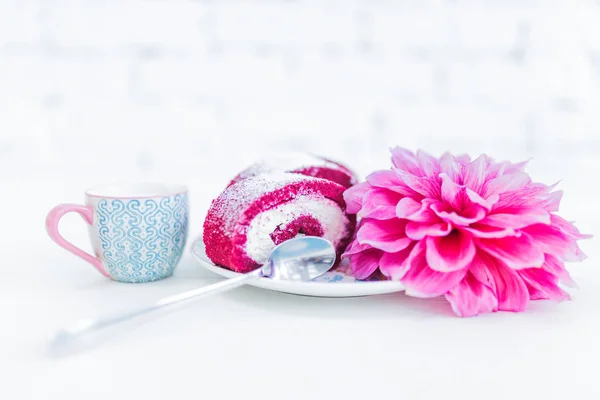 A red velvet cake roll sliced with cup of milk and flowers. — Stock Photo, Image