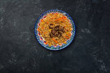 Karanlık bir arka plan üzerinde şark süsleme ile pilav plaka üzerinde. Orta-Asya Mutfağı - Plov. Üstten Görünüm